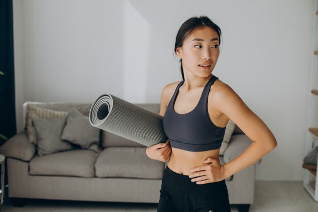 自宅でヨガマットを持つ女性