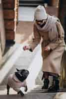 Free photo woman withg her pet french bulldog walking out