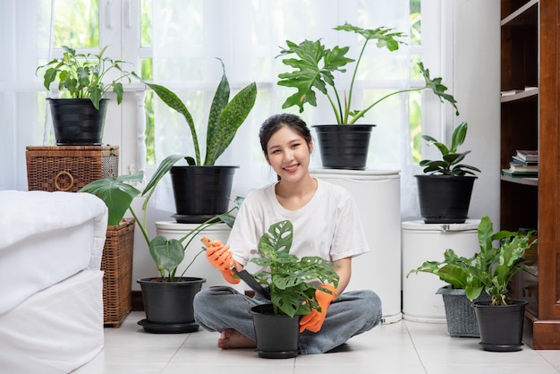 女性はオレンジ色の手袋を着用し、家に木を植えました。