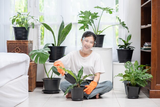 The woman wore orange gloves and planted trees in the house.