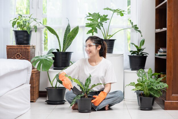 The woman wore orange gloves and planted trees in the house.