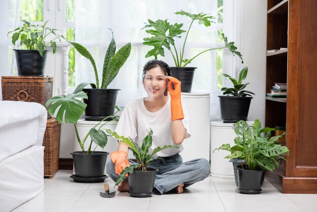 女性はオレンジ色の手袋を着用し、家に木を植えました。