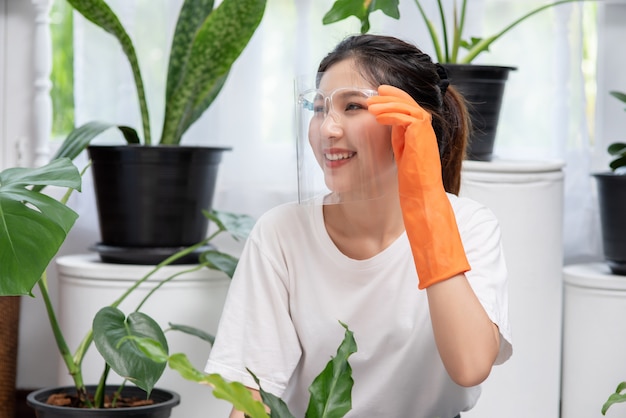 女性はオレンジ色の手袋を着用し、家に木を植えました。