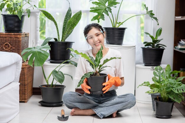 女性はオレンジ色の手袋を着用し、家に木を植えました。