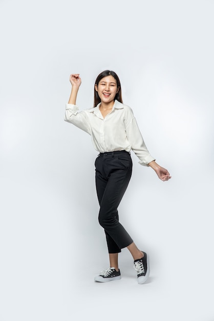 The woman wore a white shirt and dark trousers and made a fun pose