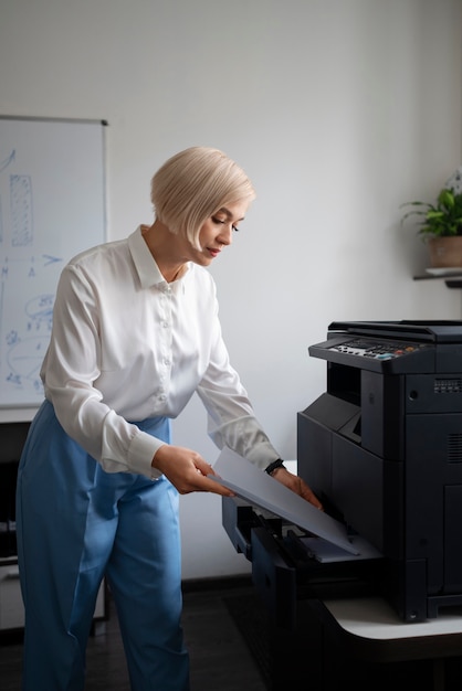 Foto gratuita donna al lavoro in ufficio utilizzando la stampante