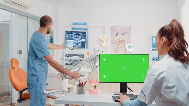 Woman working as dentist with green screen on monitor