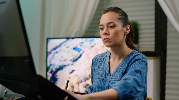 Woman working as editor with graphic tablet and stylus while retouching pictures on touch screen computer. Photographer editing images using gadget and technology. Photography artist