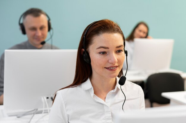 Woman working in call center office with headphones and computer