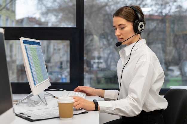 Woman working in call center office with headphones and computer