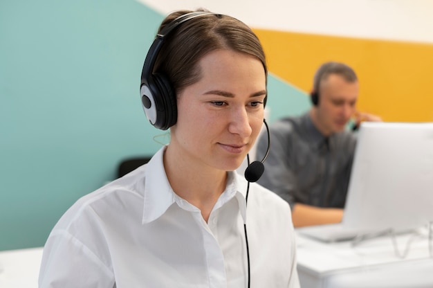 Woman working in call center office with headphones and computer