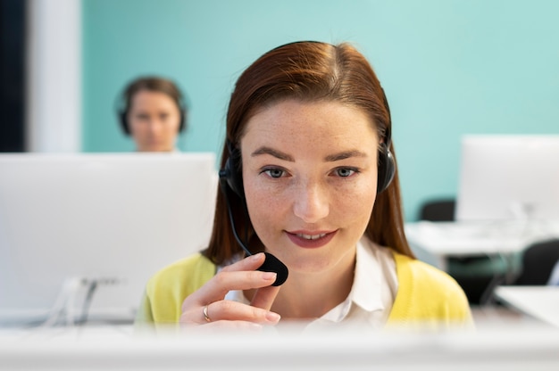 Woman working in call center office with headphones and computer