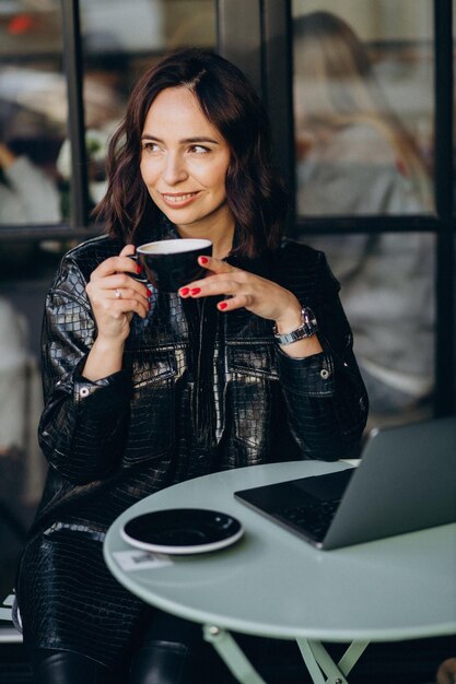 Woman working on computer in a cafe and drinking coffee