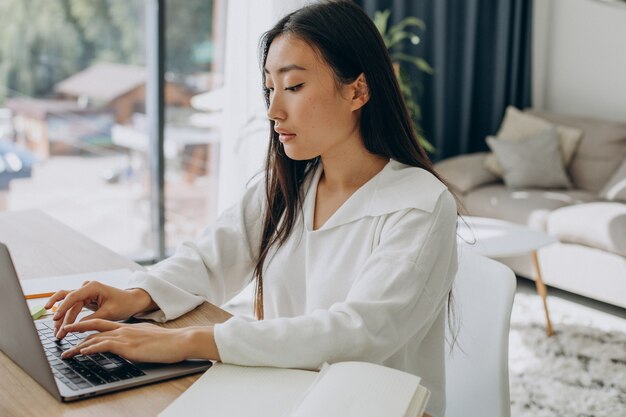 自宅の机でコンピューターに取り組んでいる女性