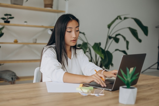 自宅の机でコンピューターに取り組んでいる女性