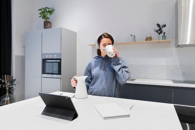 Женщина, работающая на домашней кухне с планшетом