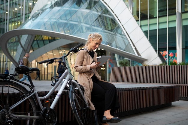 Woman working on her tablet outside and drinking coffee