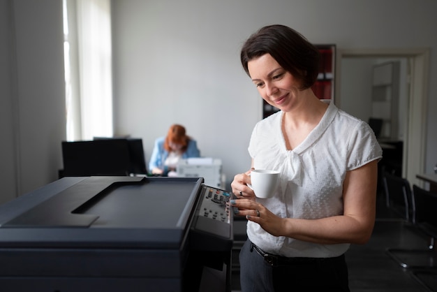 Бесплатное фото Женщина работает в офисе и использует принтер