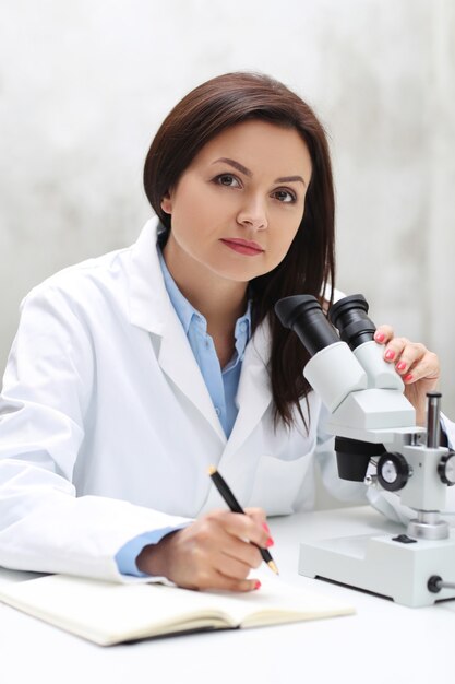 Женщина, работающая в лаборатории с микроскопом