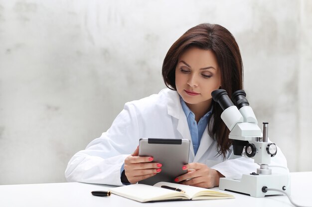 Женщина, работающая в лаборатории с микроскопом