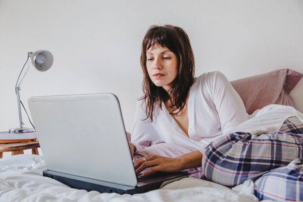 Woman working on laptop on bed