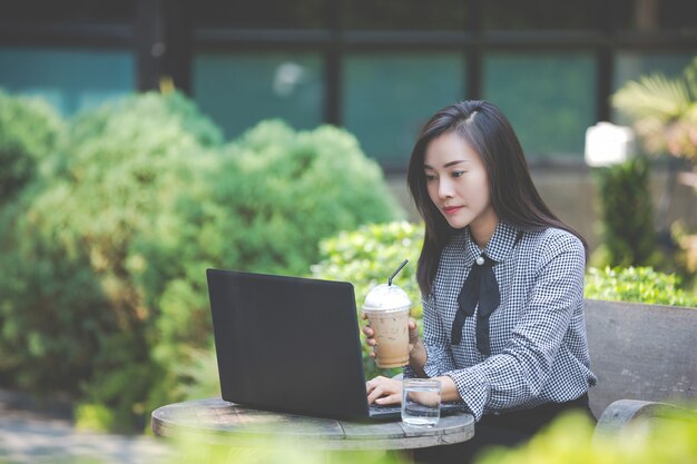 カフェのラップトップに取り組んでいると、コーヒーを飲む女性