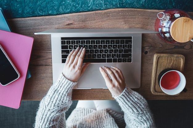 Free photo woman working on a laptop in a cafe with a cup of tea top view