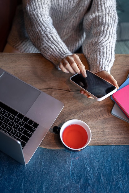 Donna che lavora su un computer portatile in un caffè con una tazza di tè vista dall'alto