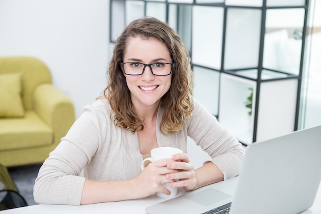 Woman Working on Laptop and Drinking Tea at Home