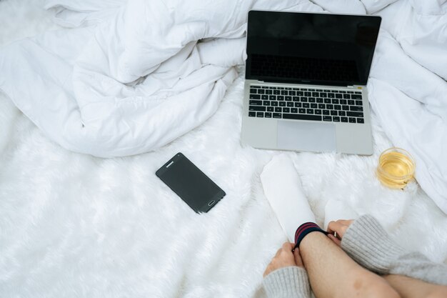 Woman working on laptop on her bed in cold day