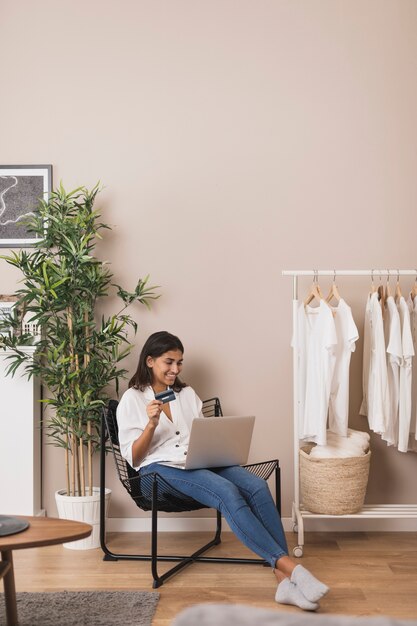 Woman working on laptop and holding a card in living room