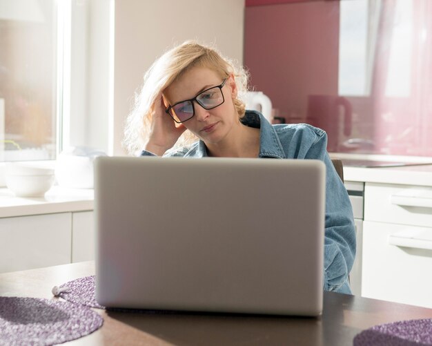 Foto gratuita donna che lavora al computer portatile in cucina