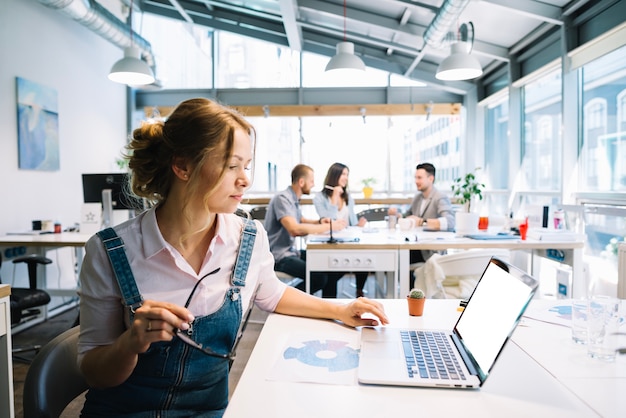 Foto gratuita donna che lavora al computer portatile in ufficio