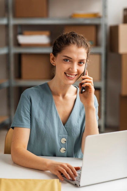 Donna che lavora al computer portatile e parla al telefono