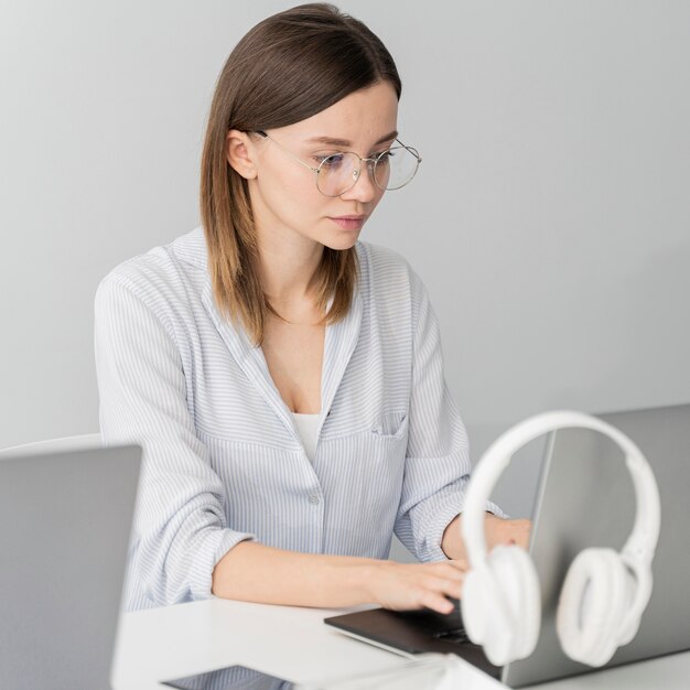 Woman working on a laptop with her headphones hanging