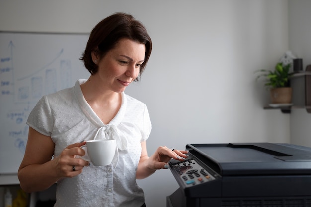 사무실에서 일하고 프린터를 사용하는 여성