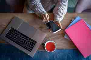 Бесплатное фото Женщина работает на ноутбуке в кафе с чашкой чая сверху