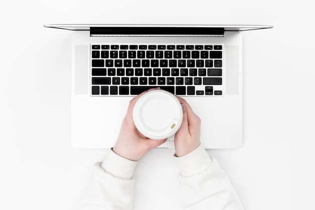 Бесплатное фото Женщина работает на ноутбуке с одноразовой чашкой, вид сверху