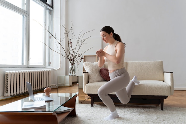 Foto gratuita donna che si allena dopo un istruttore di fitness online