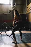 Free photo woman working out with rope in gym