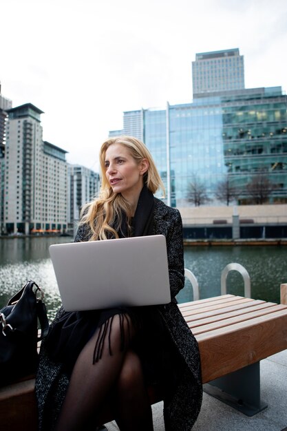 Женщина работает на улице с помощью ноутбука