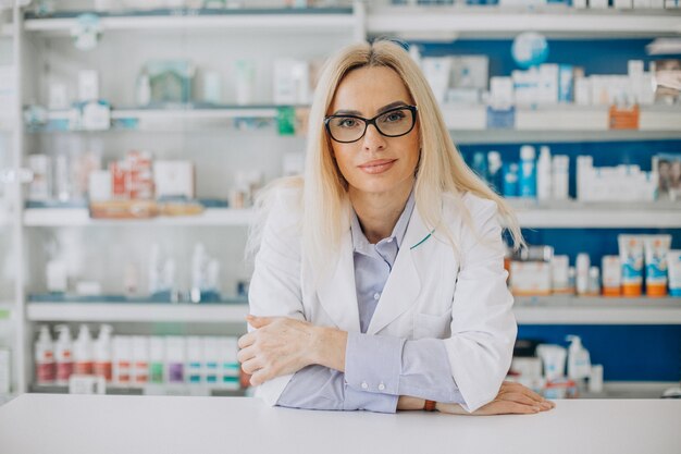 Женщина работает в аптеке и носит пальто