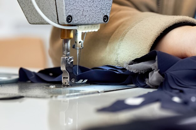 Женщина работает на швейной машине с синей тканью