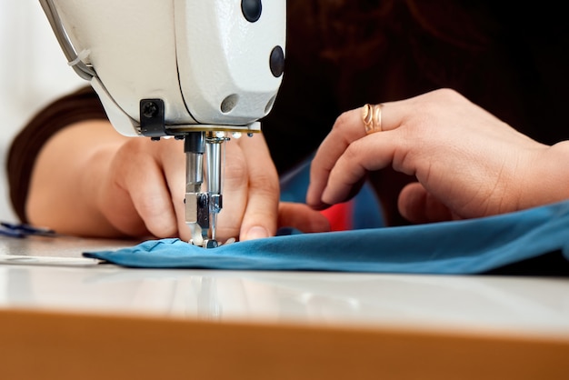 Woman working on a sewing machine with blue fabric