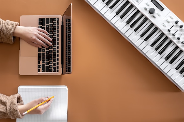 A woman works at a laptop writes music creates a song flat lay