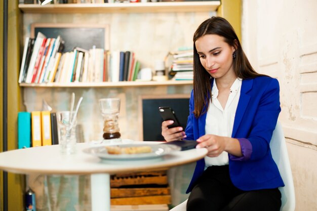 Foto gratuita la donna lavora con uno smartphone al tavolo in un caffè