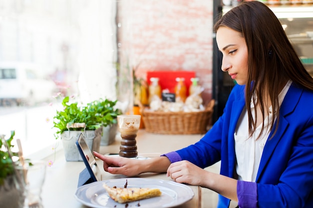 Woman works with a tablet at the table in a cafe