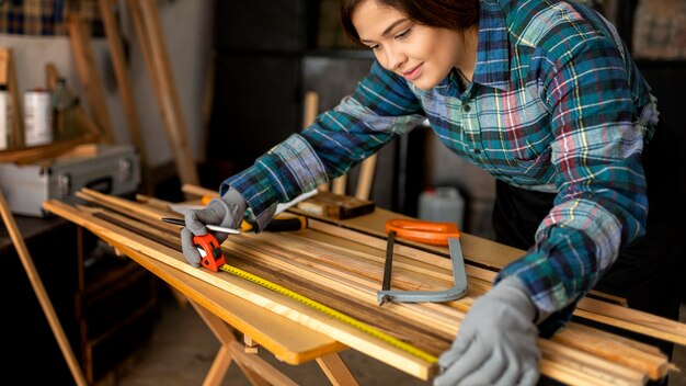 Woman in workshop measuring wood plank