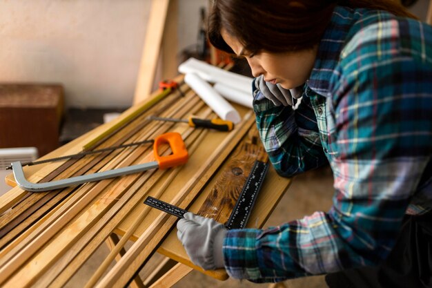 Woman in workshop measuring wood