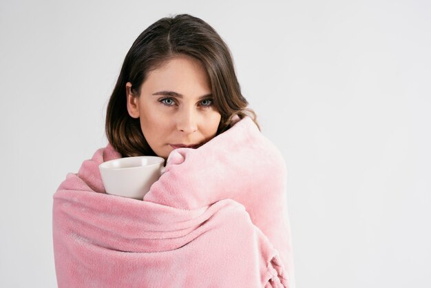 Free photo woman wrapped in blanket holding a mug of hot tea